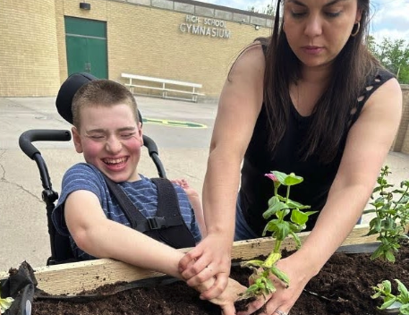 Student Planting flowers with help from teacher